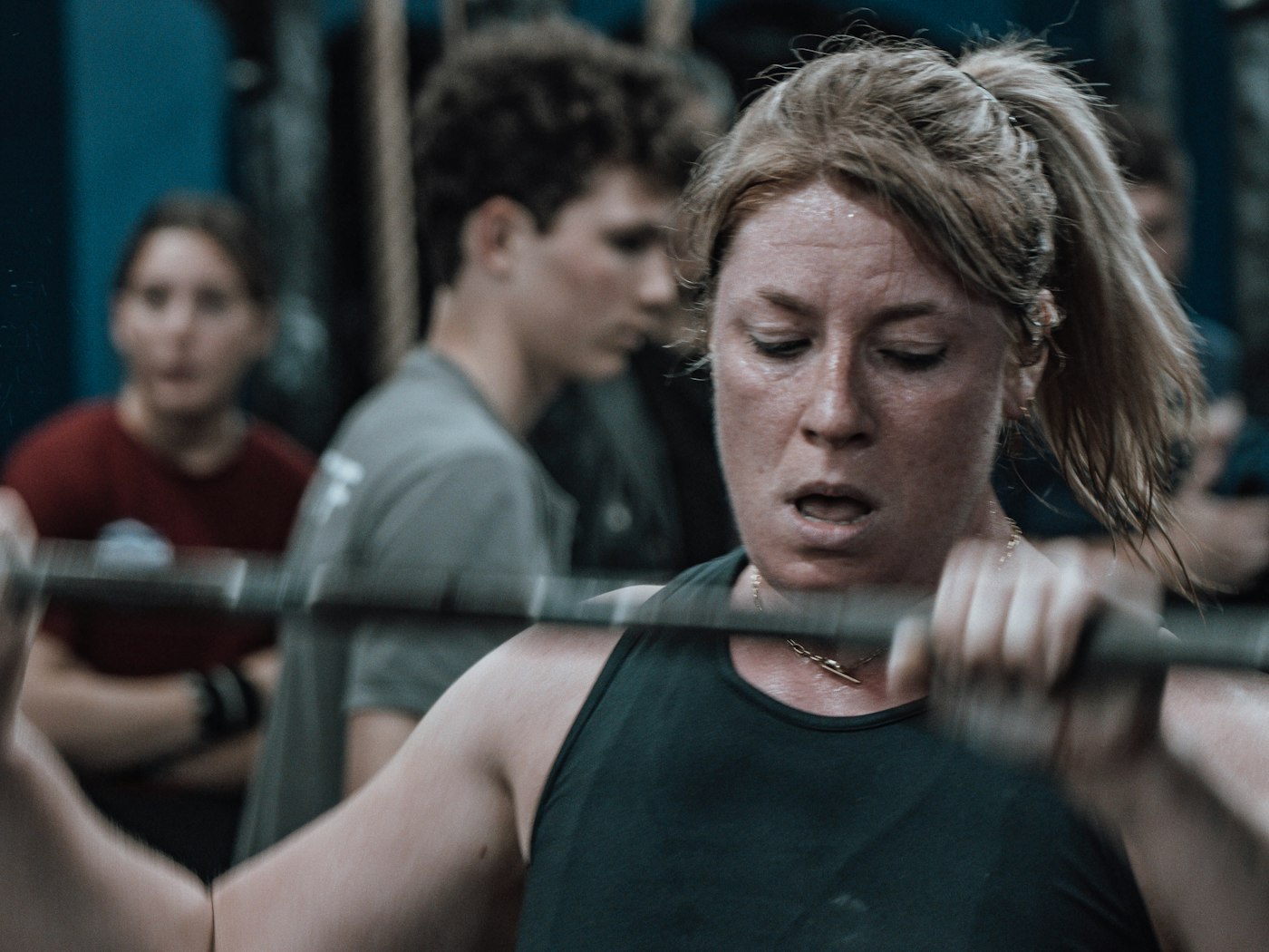 A member pressing a loaded barbell with a spotter behind